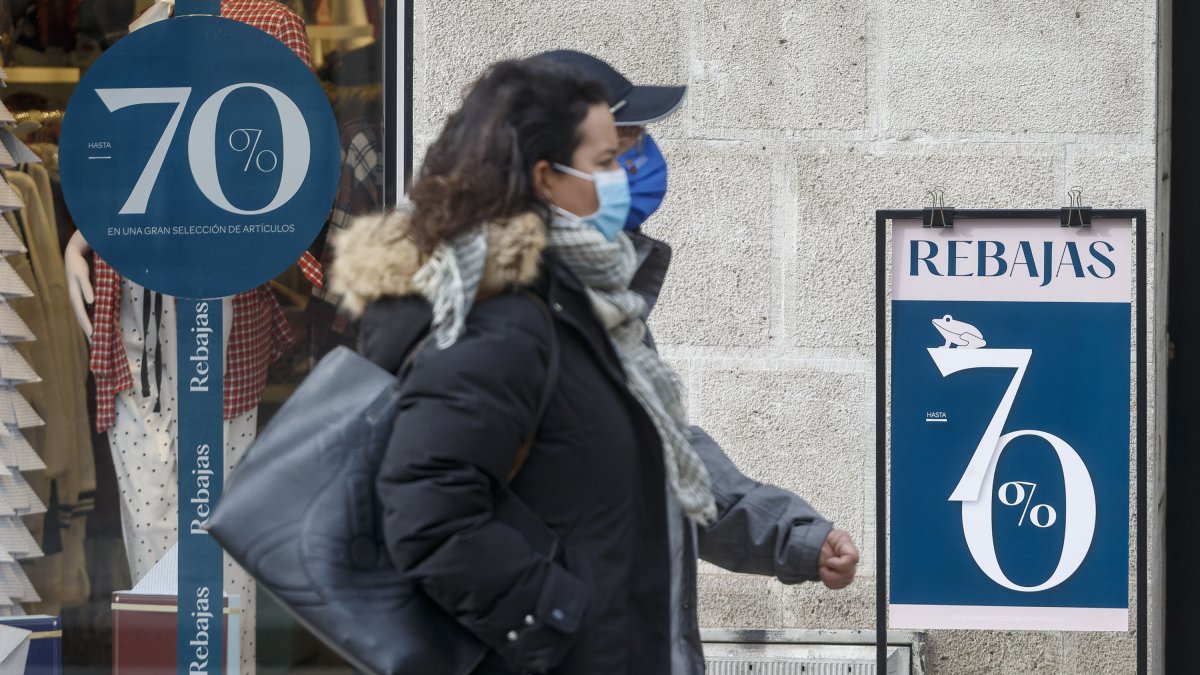 Dos personas pasan por delante de un comercio que anuncia rebajas en su escaparate. SANTI OTERO