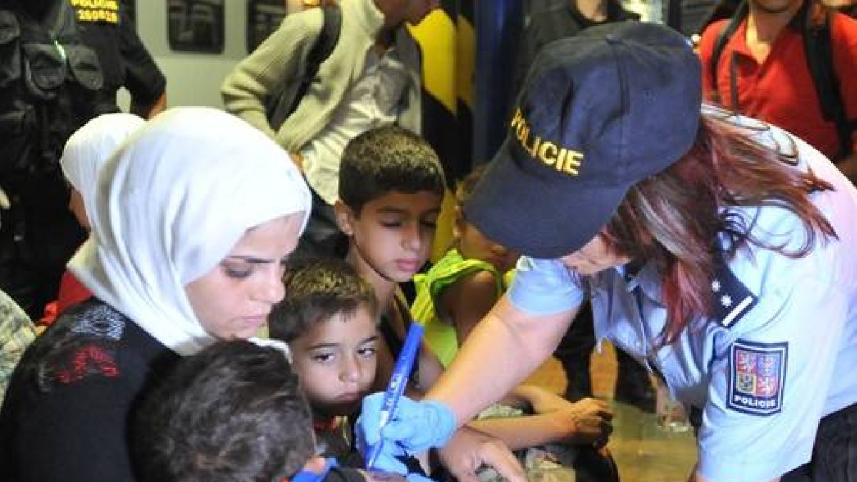 Una agente de policía checa escribe el número en la mano de un niño.-AP/IGOR ZEHL