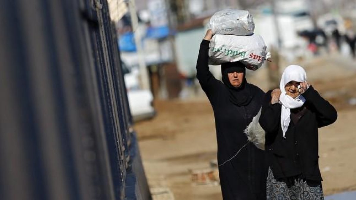 Refugiados sirios trasladan bolsas de alimentos en el paso fronterizo de Öncüpinar, en Kilis, Turquía.-SEDAT SUNA / EFE