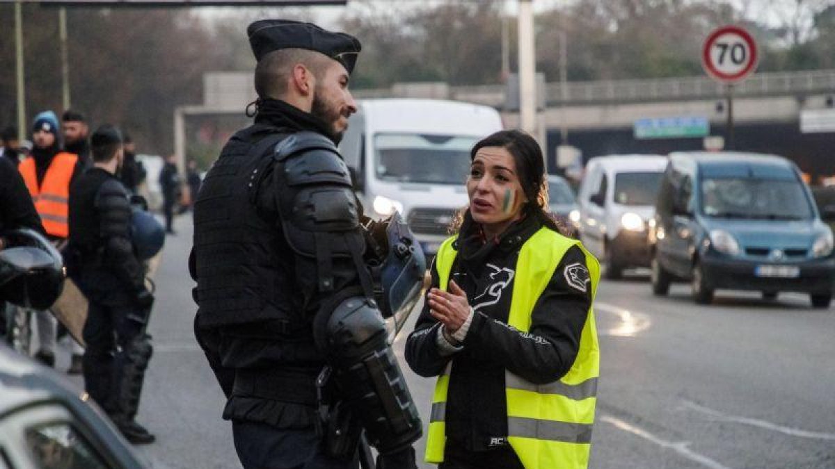 Una manifestante con el chaleco amarillo, símbolo de la protesta, habla con un policía, esta mañana en los alrededores de París.-EPA