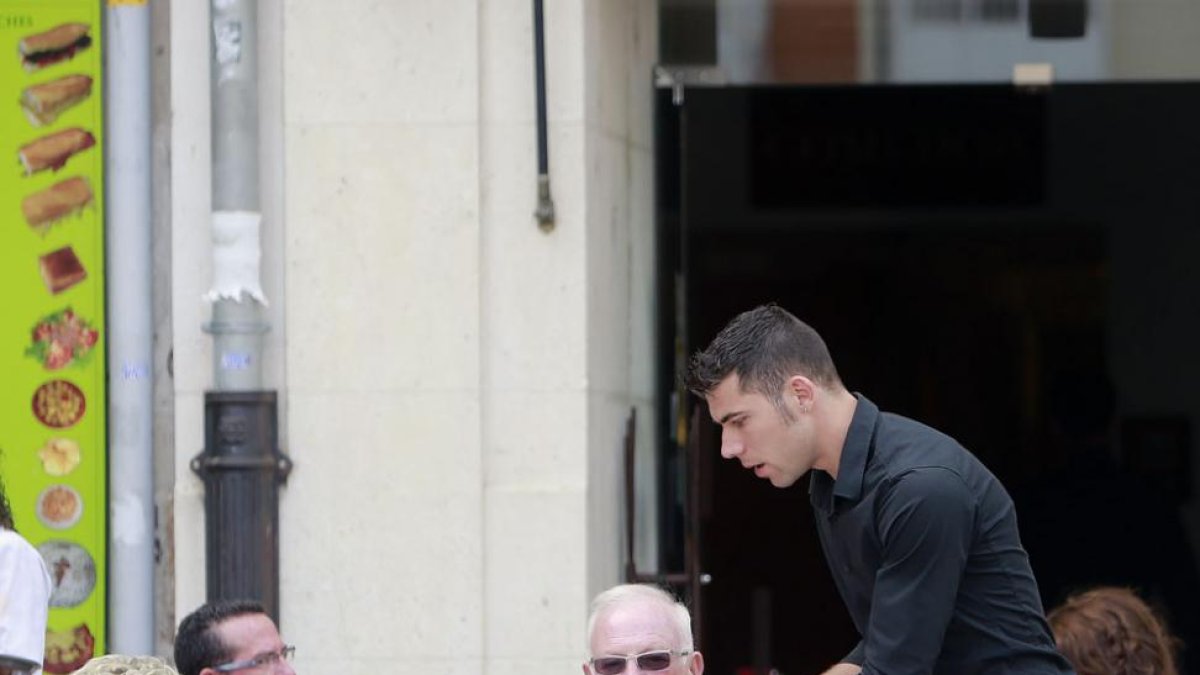 Un camarero atiende una mesa en una terraza de Burgos. El paro en el sector Servicios es el que más baja.-RAÚL OCHOA