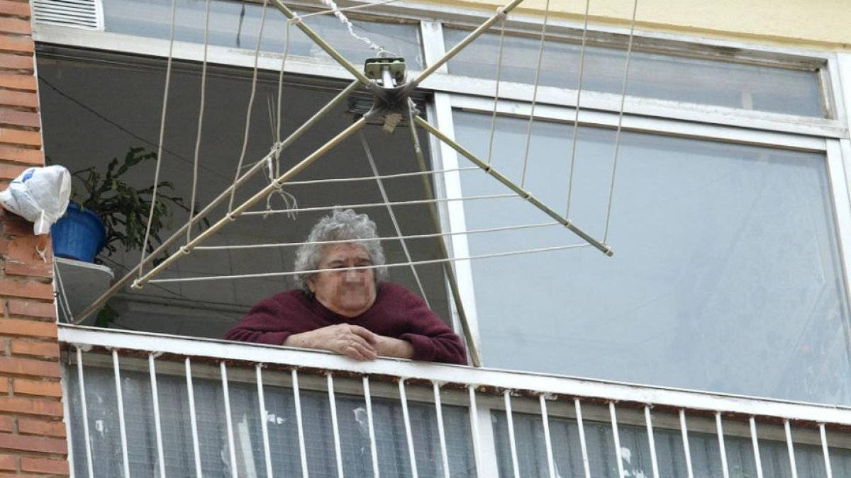 Una mujer mayor asomada a la terraza de su vivienda en la capital burgalesa.-ISRAEL L. MURILLO