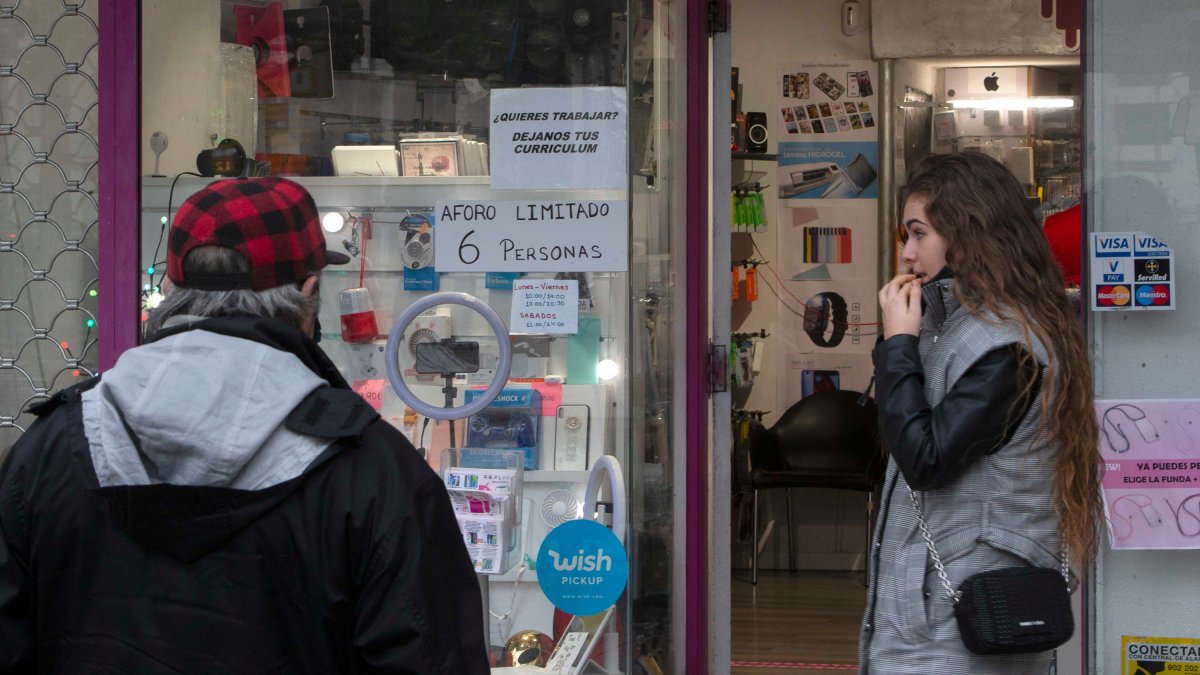 Un hombre espera fuera de un comercio de la zona centro que luce un cartel reclamando currículums para ofrecer un puesto de trabajo. RAÚL G. OCHOA
