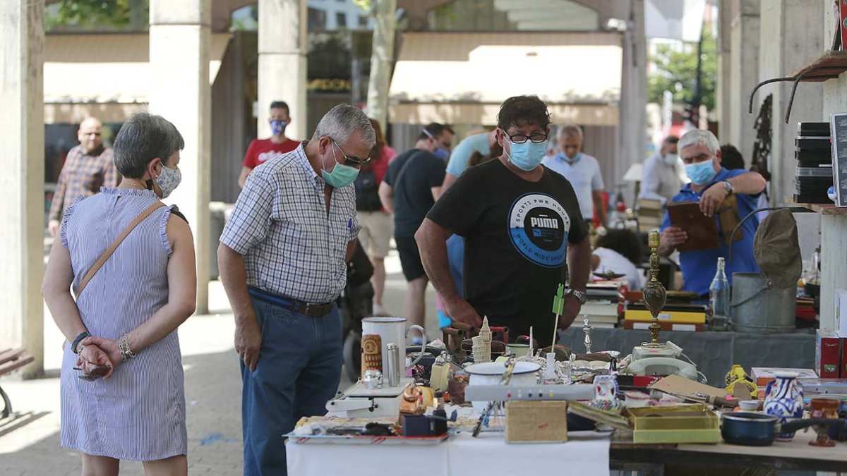 Varias personas ven los productos de uno de los puestos en el mercadillo de la plaza de España. ECB