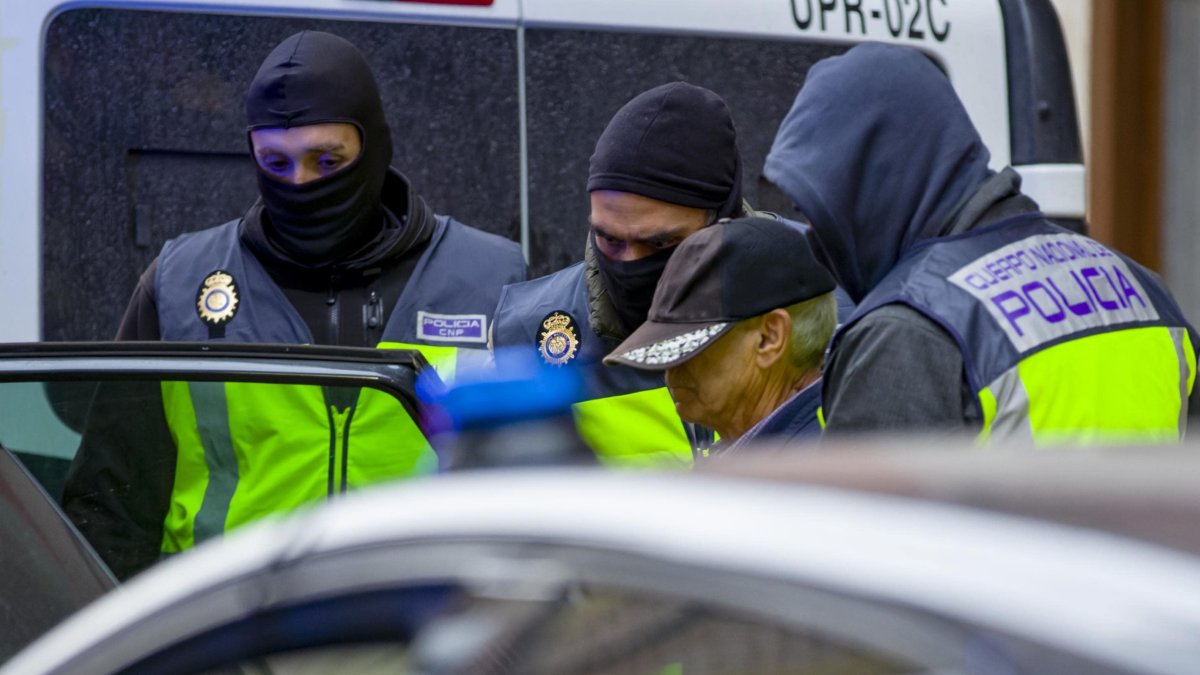 El detenido junto a los agentes durante el registro de su domicilio. ICAL