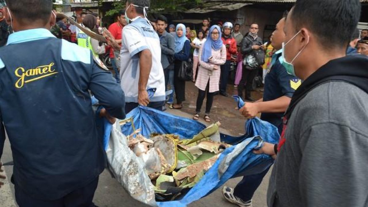 Oficiales indonesios cargando resto del avión militar.-AMAN ROCHMAN / AFP