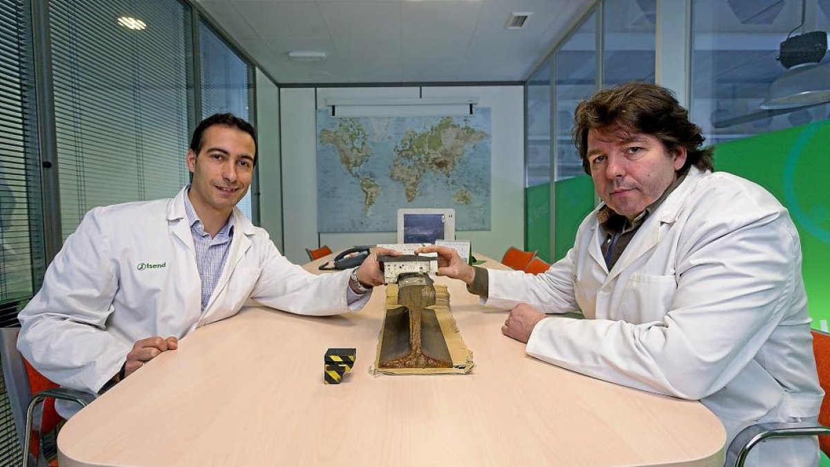 Dos ingenieros de la empresa vallisoletana Isend muestran un trozo de riel por el que corre el tren.-PHOTOGENIC