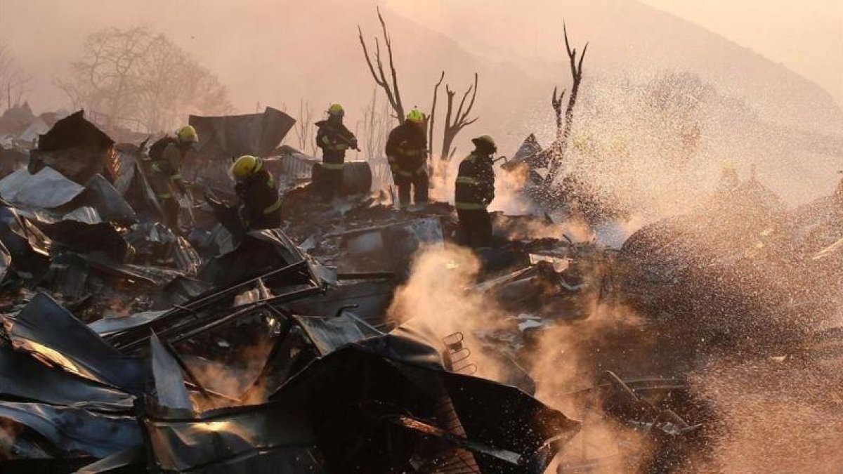 Un grupo de bomberos trabaja entre los escombros de varias casas devoradas por las llamas en Valparaiso.-REUTERS / RODRIGO GARRIDO