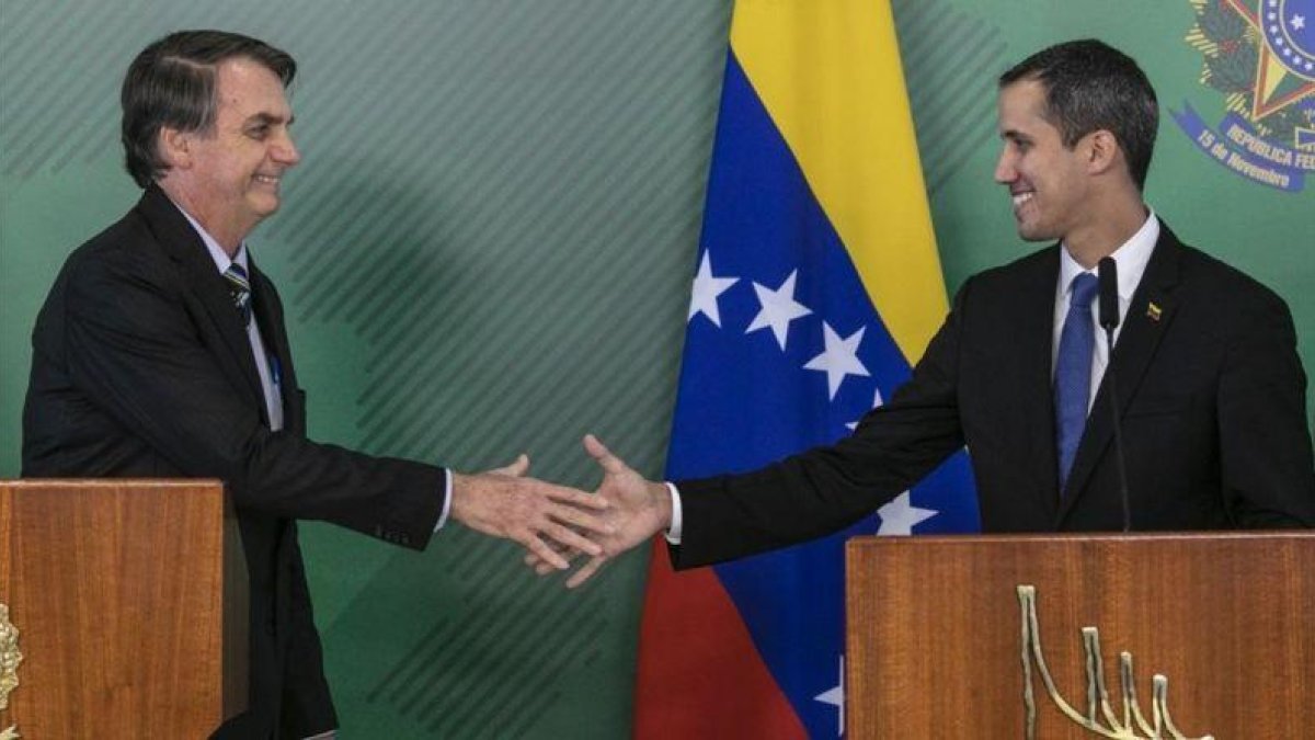 El presidente de Brasil, Jair Bolsonaro (izquierda), y el líder opositor y autoproclamado presidente venezolano, Juan Guaidó, se saludan durante el encuentrpo que mantuvieron este jueves en Brasilia.-SERGIO LIMA (AFP)