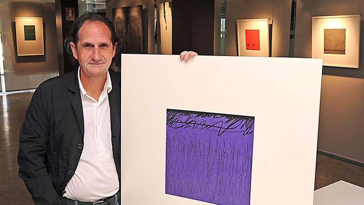 Gerardo Ibáñez sujeta una de las pinturas que componen 'En clave de FA', en la sede del Colegio de Arquitectos Técnicos.-Israel L. Murillo