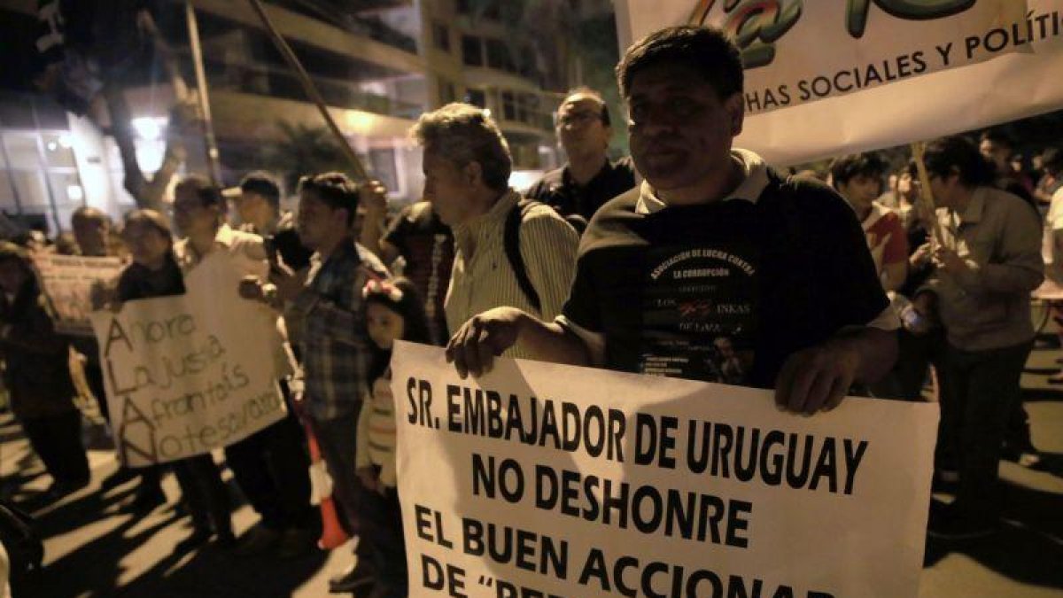 Un grupo de simpatizantes apristas gritan arengas a favor del lider politico peruano Alan Garcia en los exteriores de la residencia del embajador de Uruguay en la ciudad de Lima Peru.-EFE / ERNESTO ARIAS