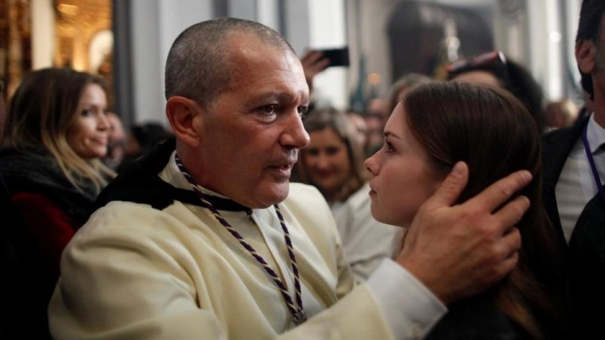 Antonio Banderas abraza a su hija, Estela del Carmen, antes de salir como penitente de Las Lágrimas. A la izquierda, la novia del actor, Nicole Kimpel.-/ REUTERS
