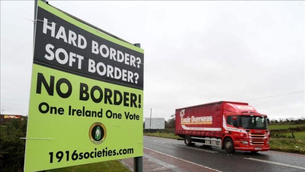 Un automóvil circula junto a un cartel que reclama que no haya frontera entre Irlanda e Irlanda del Norte.-PAUL FAITH (AFP)