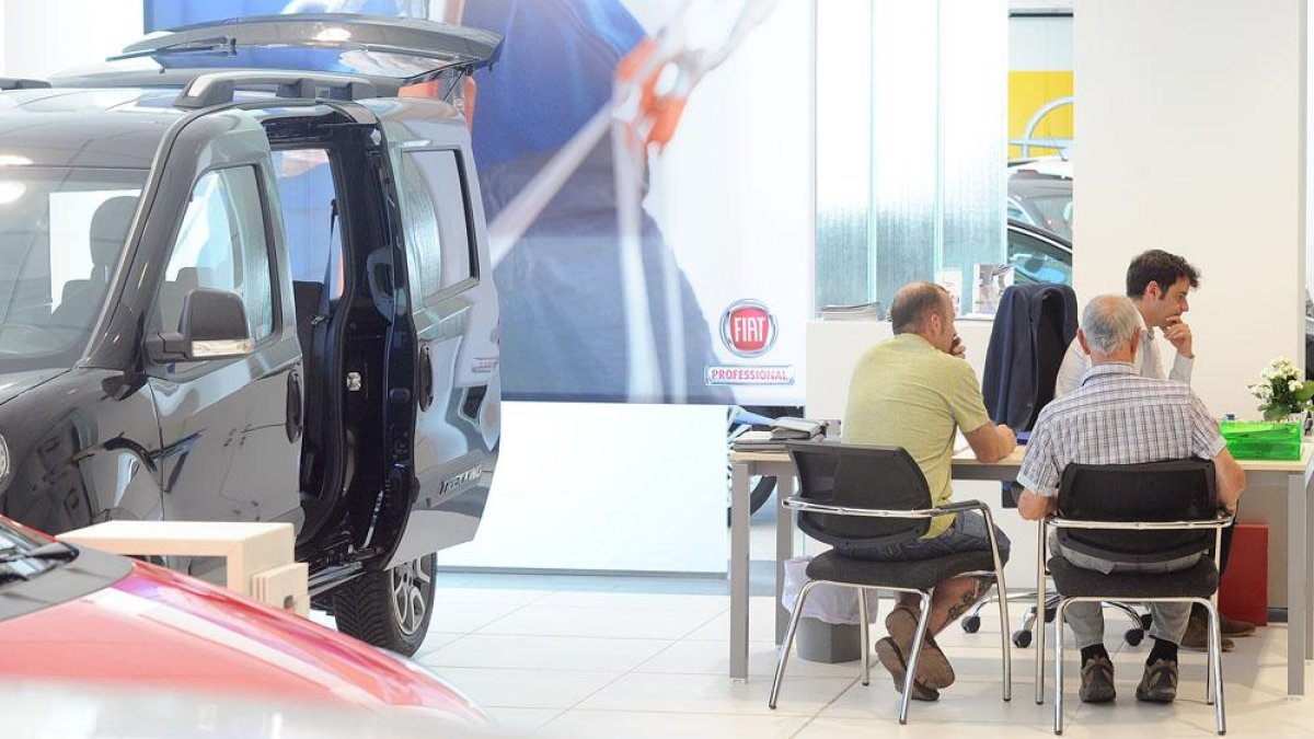 Dos hombres hablan con un comercial en un concesionario de la capital burgalesa.-ISRAEL L. MURILLO