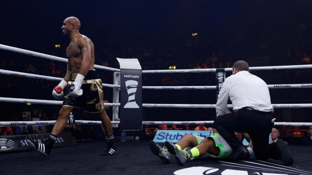 El boxeador Louis Adolphe da vueltas por el ring tras noquear a traición a Nathan McIntosh, atendido por el árbitro en la lona.-RUETERS / ANDREW COULDRIDGE
