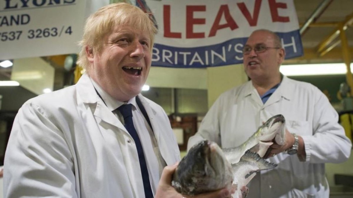 Un exultante Boris Johnson (izquierda) sostiene un salmón salvaje junto a Greg Essex, en el mercado de pescado de Billingsgate, en Londres, este miércoles.-AP / STEFAN ROUSSEAU
