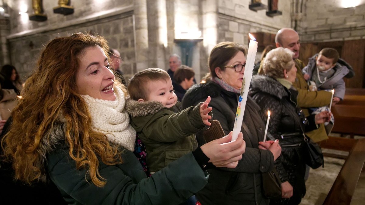Hugo intenta coger la vela que sostiene su madre Lorena durante la ceremonia. TOMÁS ALONSO