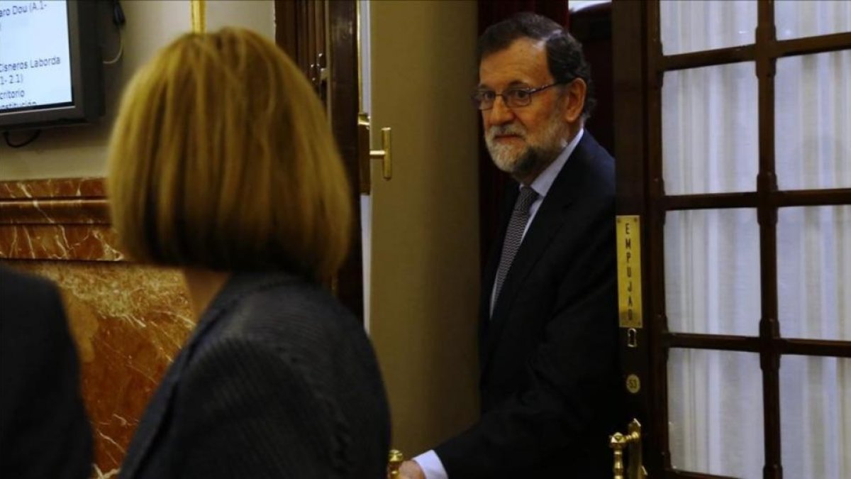 El presidente del Gobierno, Mariano Rajoy, y la ministra de Defensa, María Dolores de Cospedal, en los pasillos del Congreso.-AGUSTÍN CATALÁN