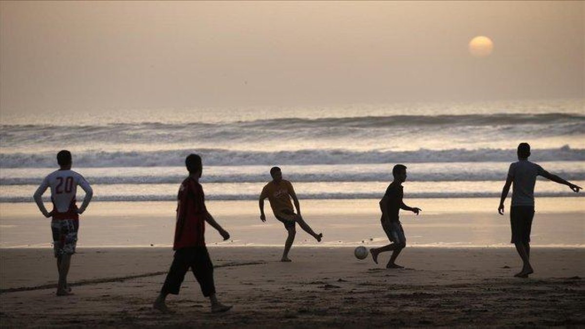 Jóvenes marroquíes jugando a fútbol en la playa de Agadir, al sur del país.-CRISTOPHE ENA (AP)