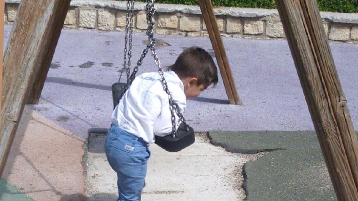 Un niño juega en un columpio con el suelo roto.-L. VELÁZQUEZ