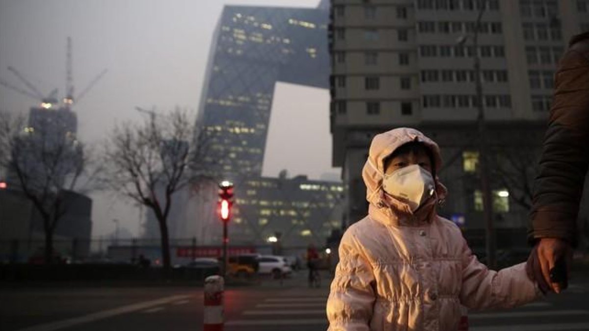 Una niña con una máscara protectora para la contaminación en Pekín, este lunes.-EFE