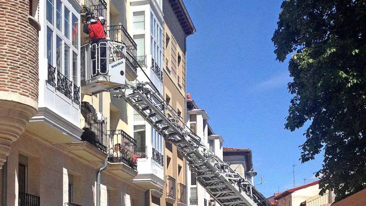 Los bomberos intervienen en un edificio de Fernán González, donde ayer se cayó parte de la fachada.-ISRAEL L. MURILLO