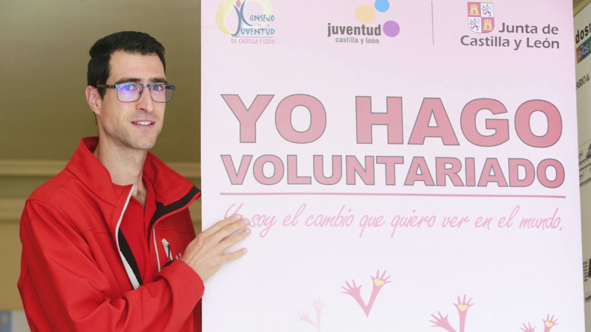 Un joven sostiene un cartel que promociona el voluntariado. ECB