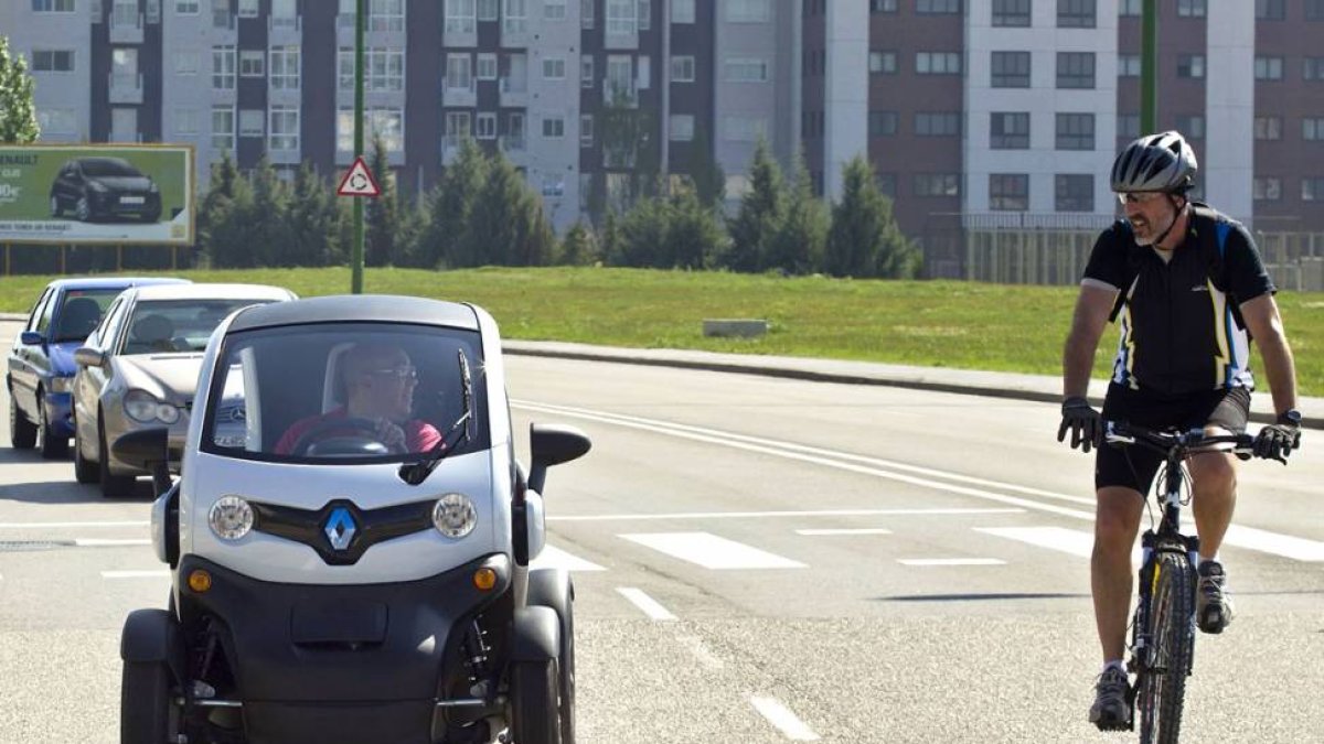 Un coche eléctrico circula junto a un ciclista.-ISRAEL L. MURILLO