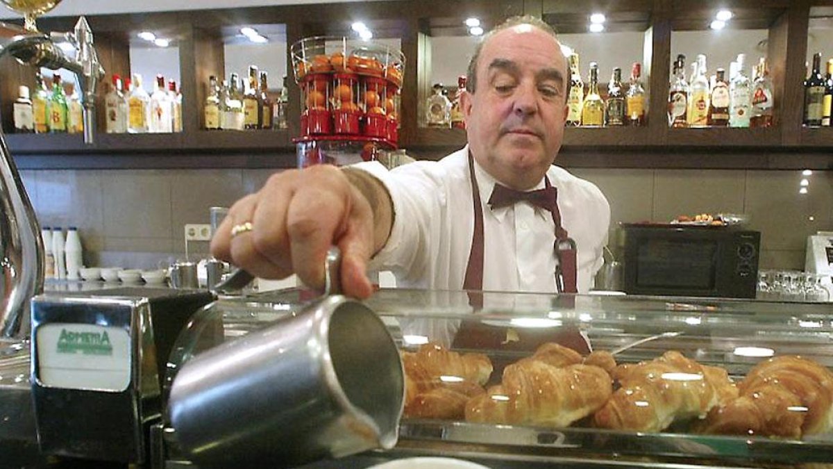 Un camarero sirve un café con leche a un cliente.-QUIQUE PALA