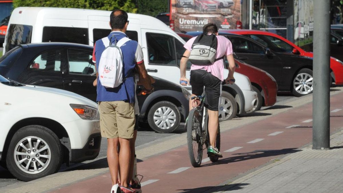 Un hombre en patinete eléctrico compartiendo con un ciclista el carril bici.