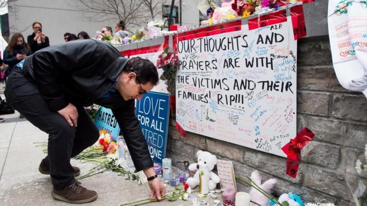 Un hombre coloca una flor en el memorial improvisado a las víctimas del atropello en Toronto.-/ NATHAN DENETTE / AP
