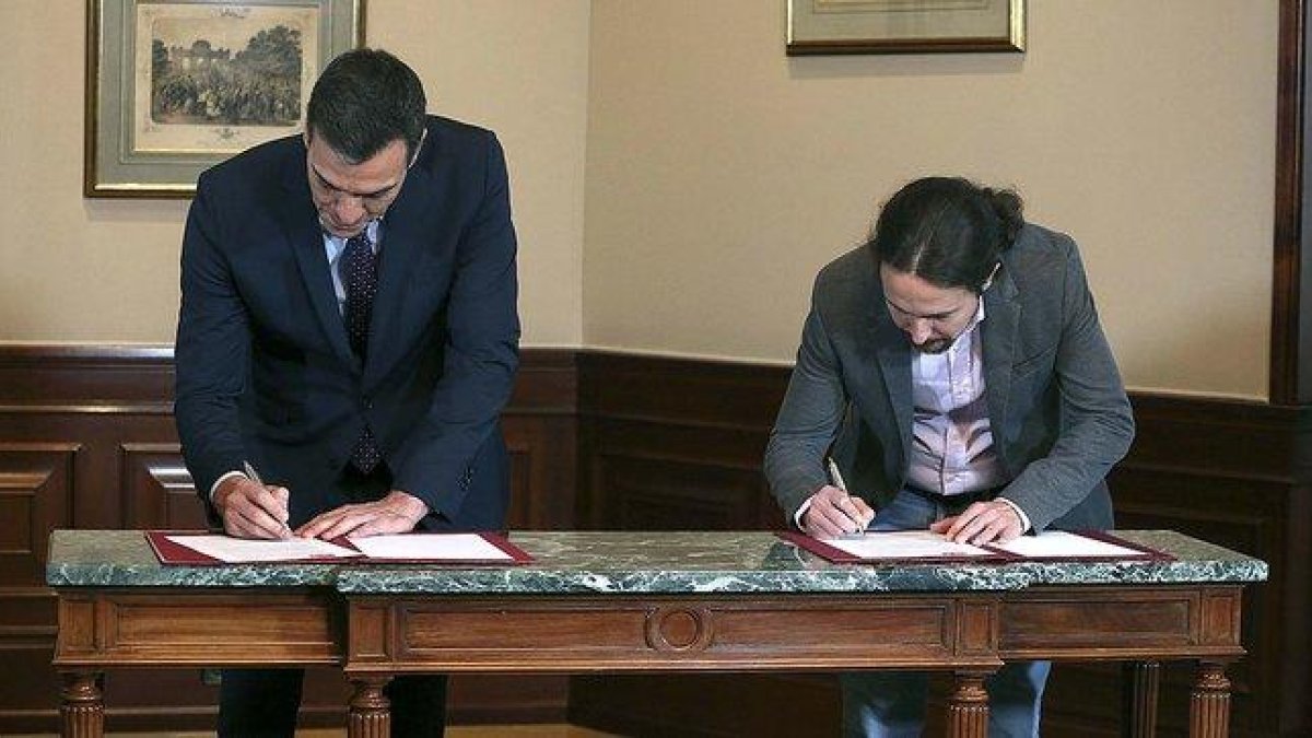Pedro Sánchez y Pablo Iglesias firman el preacuerdo de coalición, el martes pasado en el Congreso.-DAVID CASTRO