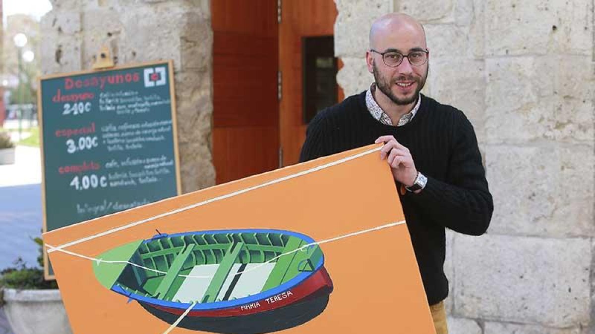 Alonso Cuesta sujeta una de las pinturas de la pequeña colección en la puerta del bar donde se exhiben.-Raúl Ochoa