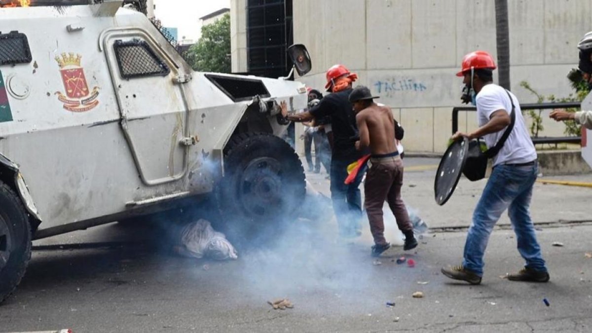 Un manifestante yace bajo una tanqueta policial en Caracas.-FEDERICO PARRA