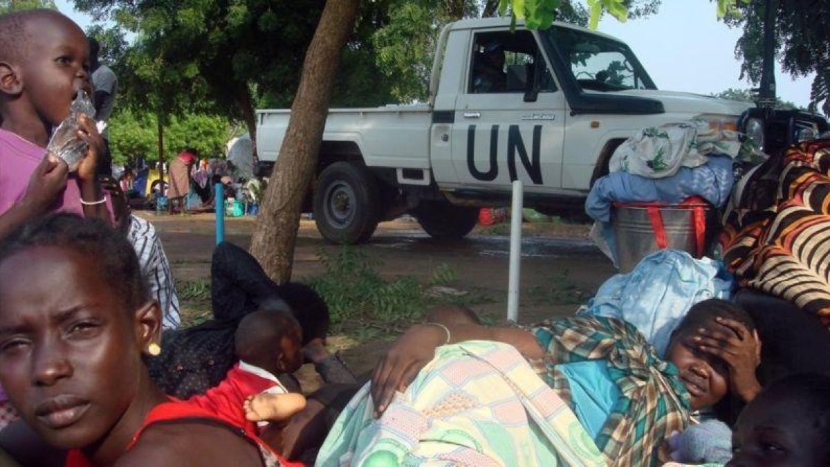 Un vehículo de la ONU junto a familias desplazadas de Sudán del Sur, en la misión de las Naciones Unidas en Tomping (Yuba), el 11 de julio del 2016.-REUTERS