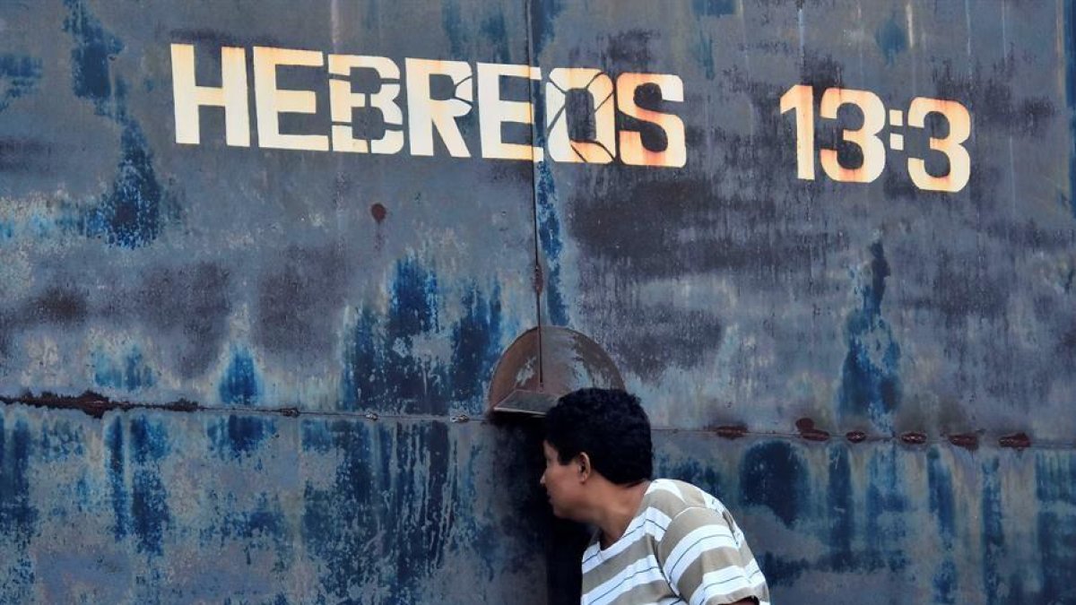 Una mujer observa por una rendija en una puerta del centro penitenciario de Tela, este sábado.-EFE / JOSÉ VALLE