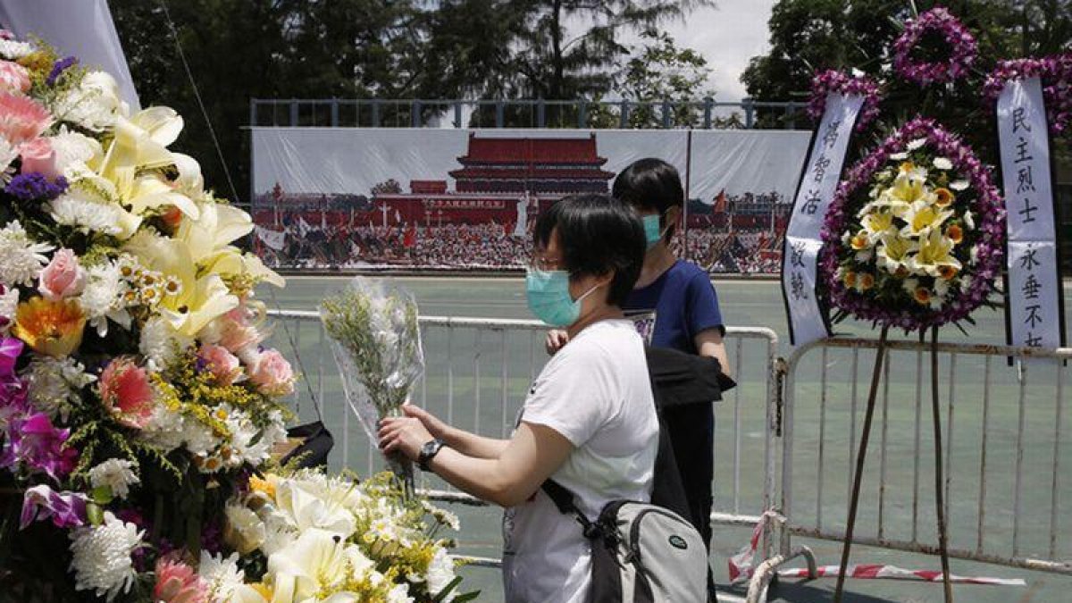 Dos mujeres colocan flores en el memorial a las víctimas de Tiananmen, en Hong Kong.-KIN CHEUNG (AP / KIN CHEUNG)