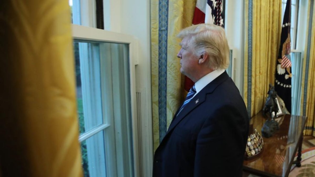Trump mira por una ventana del Despacho Oval durante la entrevista con motivo de sus 100 días en la Casa Blanca.-CARLOS BARRIA