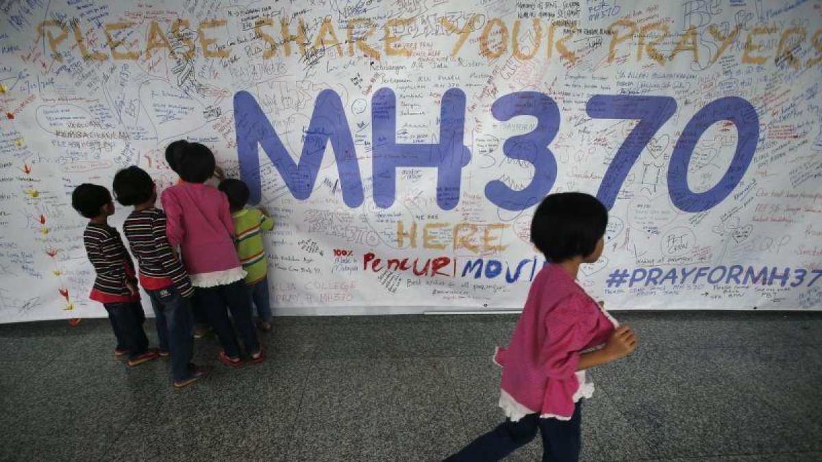 Un grupo de niños escribiendo mensajes esperanzadores para los familiares de las personas que desaparecieron en el vuelo MH370, de la compañía Malasya Airlines, en mayo del 2014.-AP / WONG MAYE-E (AP)