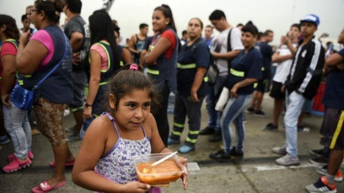 Una niña lleva su ración de comida servida durante una protesta social en Buenos Aires contra la pobreza, el 15 de marzo.-AFP / EITAN ABRAMOVICH