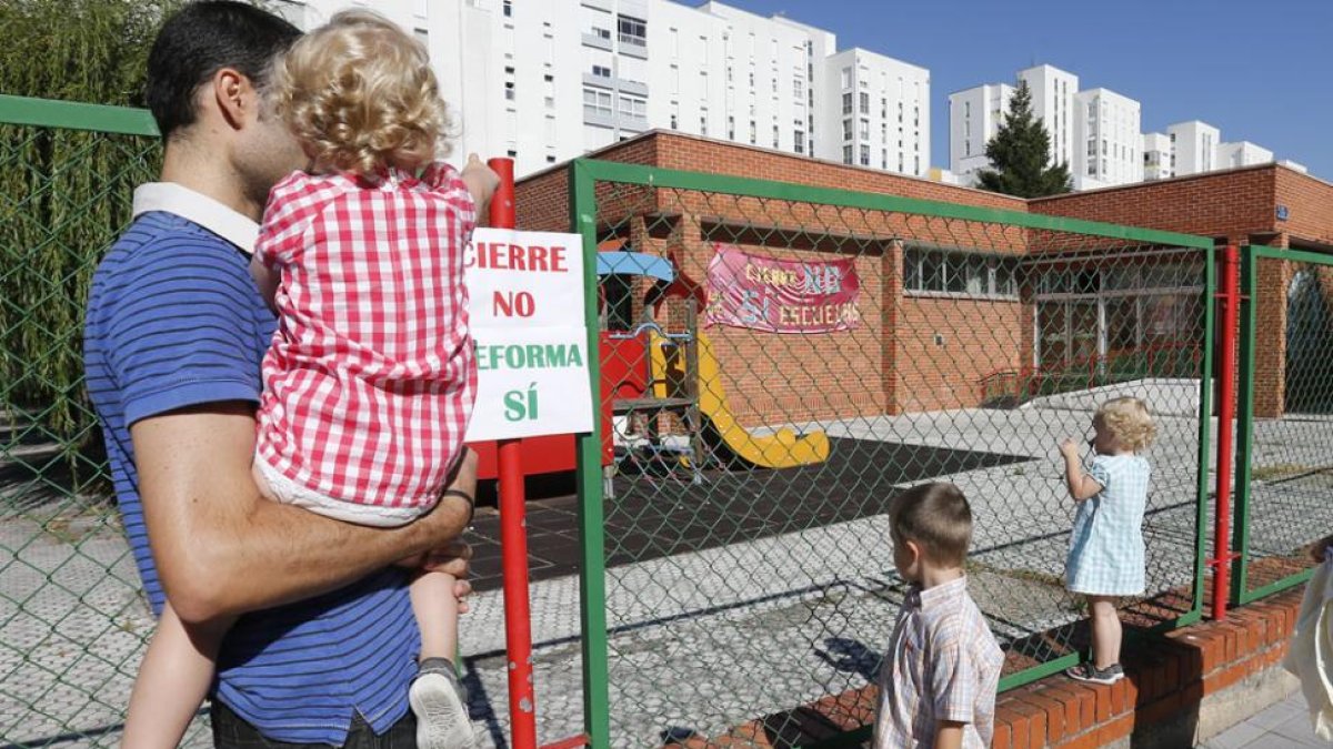 Un padre con su hijo y otros niños observan desde el exterior la guardería donde se exige que no se cierre.-SANTI OTERO