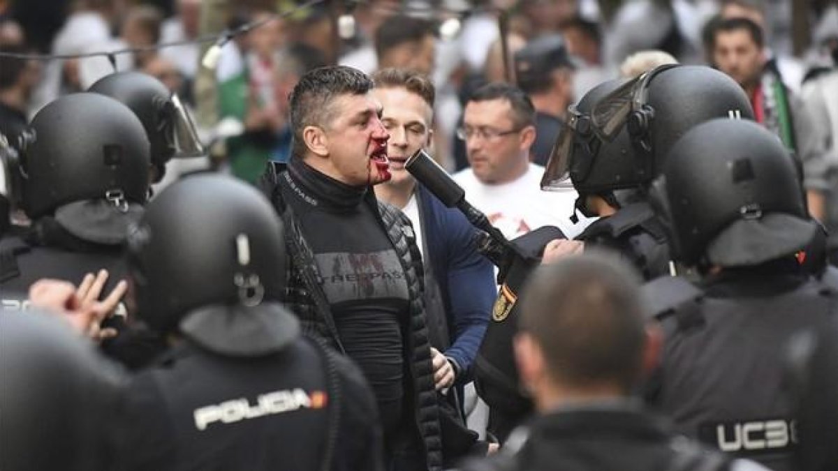 Un hincha polaco con la cara ensangrentada se enfrenta a los antidisturbios, esta tarde junto al Bernabéu.-EFE