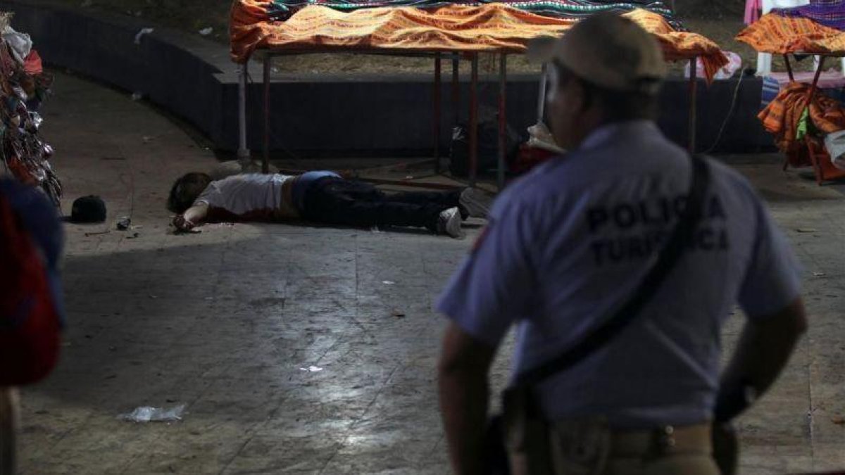Un policía frente a un hombre asesinado en Acapulco.-REUTERS