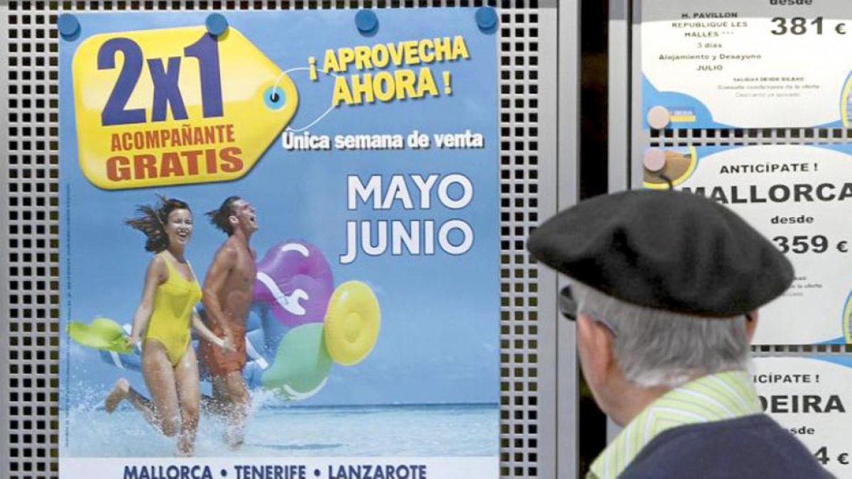 Un hombre mira una oferta en el escaparate de una agencia de viajes.-ECB