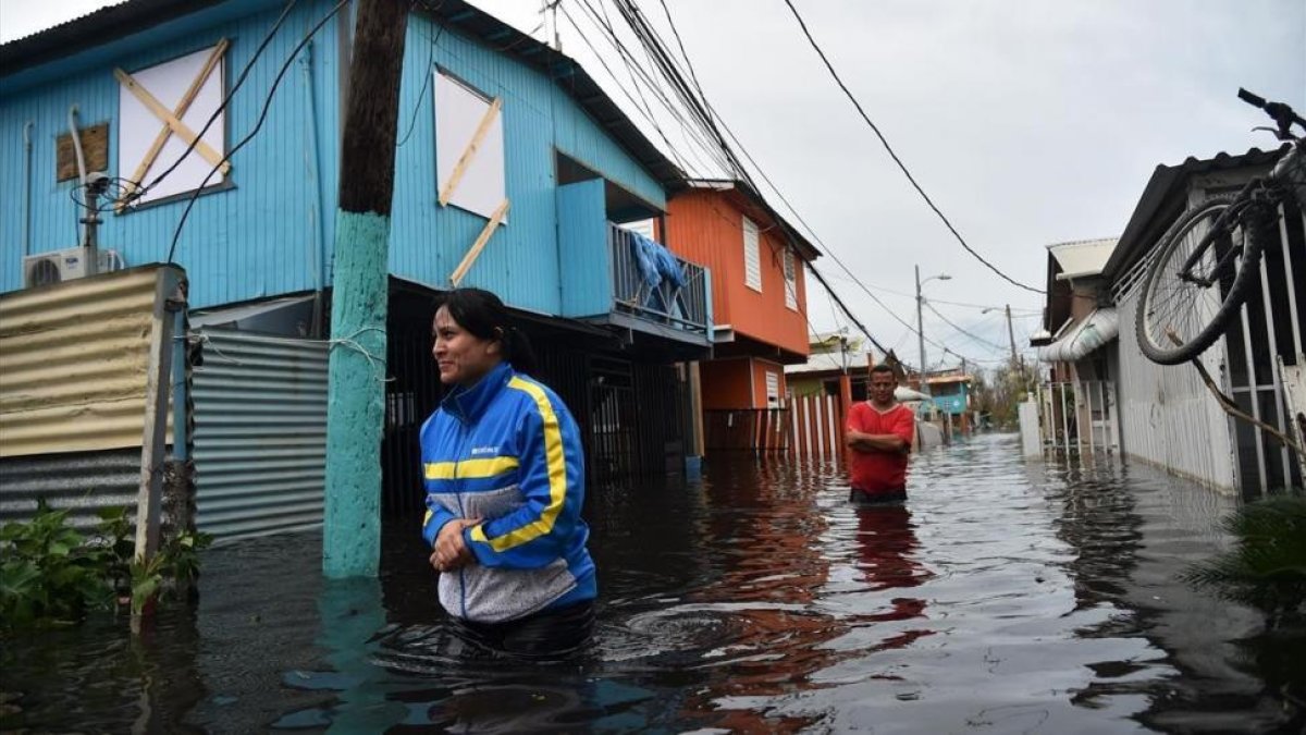 Dos personas caminan por una calle inundada en Juana Matos (Puerto Rico), el 21 de septiembre-AFP / HECTOR RETAMAL