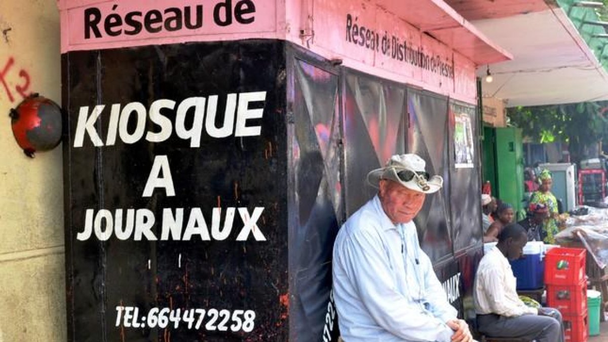 Un hombre sentado delante de un quiosco cerrado en Guinea.-CELLOU BINANI / AFP