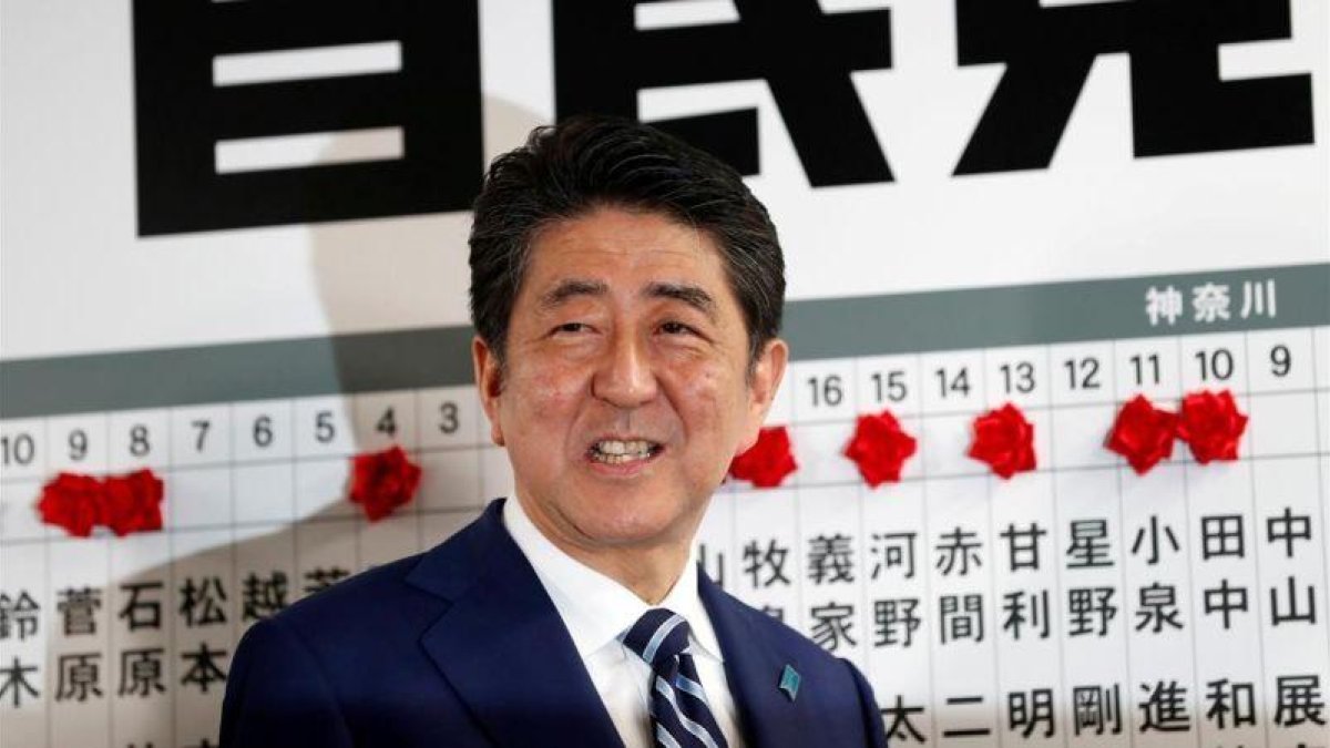 Abe sonríe mientras se dispone a colocar una rosa sobre el nombre de un candidato elegido para la Cámara baja, en la sede de su partido, en Tokio, el 22 de octubre.-REUTERS / KIM KYUNG-HOON