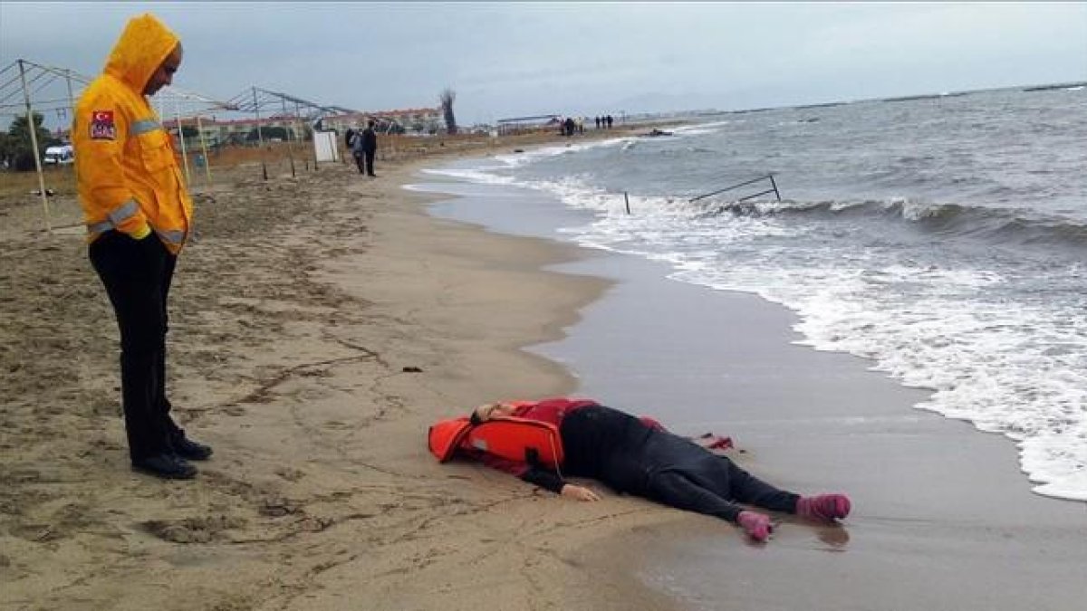 Un miembro de los equipos de rescate contempla el cuerpo de un inmigrante sobre la playa en Ayvalink (Turquía).-AP