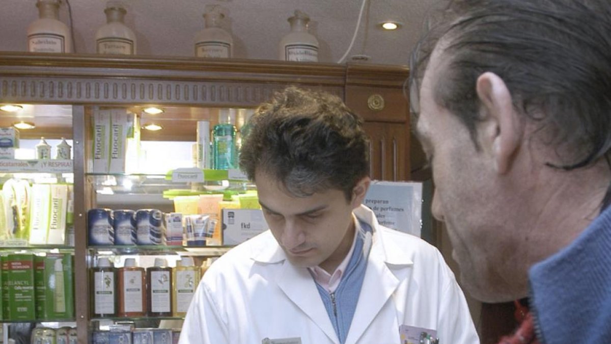 Un farmacéutico dispensa un medicamento a un hombre.-ISRAEL L. MURILLO