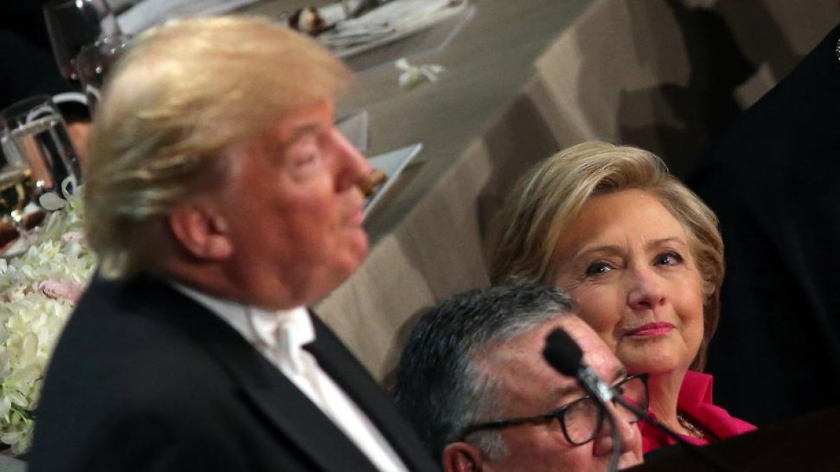 Clinton, sentada junto al obispo de Nueva York, observa a Trump durante su intervención en la cena benéfica del jueves.-REUTERS / CARLOS BARRIA